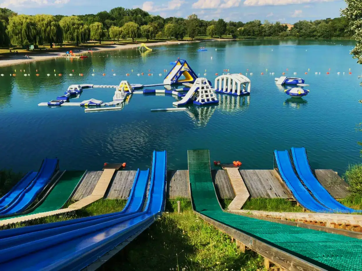 Bunte Wasserrutschen f&uuml;hren zum lauterbourg see, wo aufblasbare Hindernisse f&uuml;r Spa&szlig; sorgen.