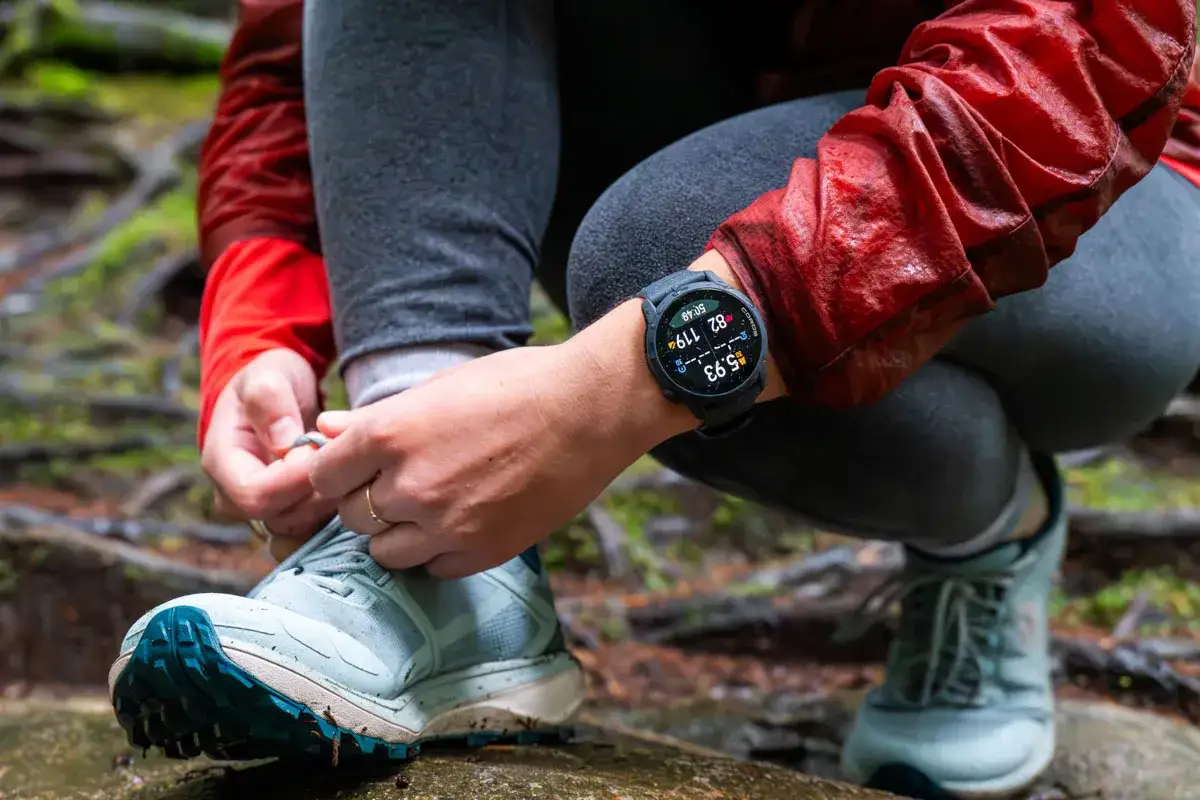 Person knyter skosnören, redo för en löprunda. Klockan visar 5.93 km, redo för nästa mil.