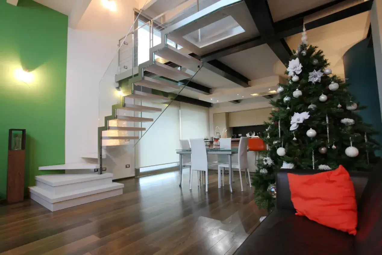 Moderno soppalco casa con scala a sbalzo, albero di Natale decorato e zona pranzo.