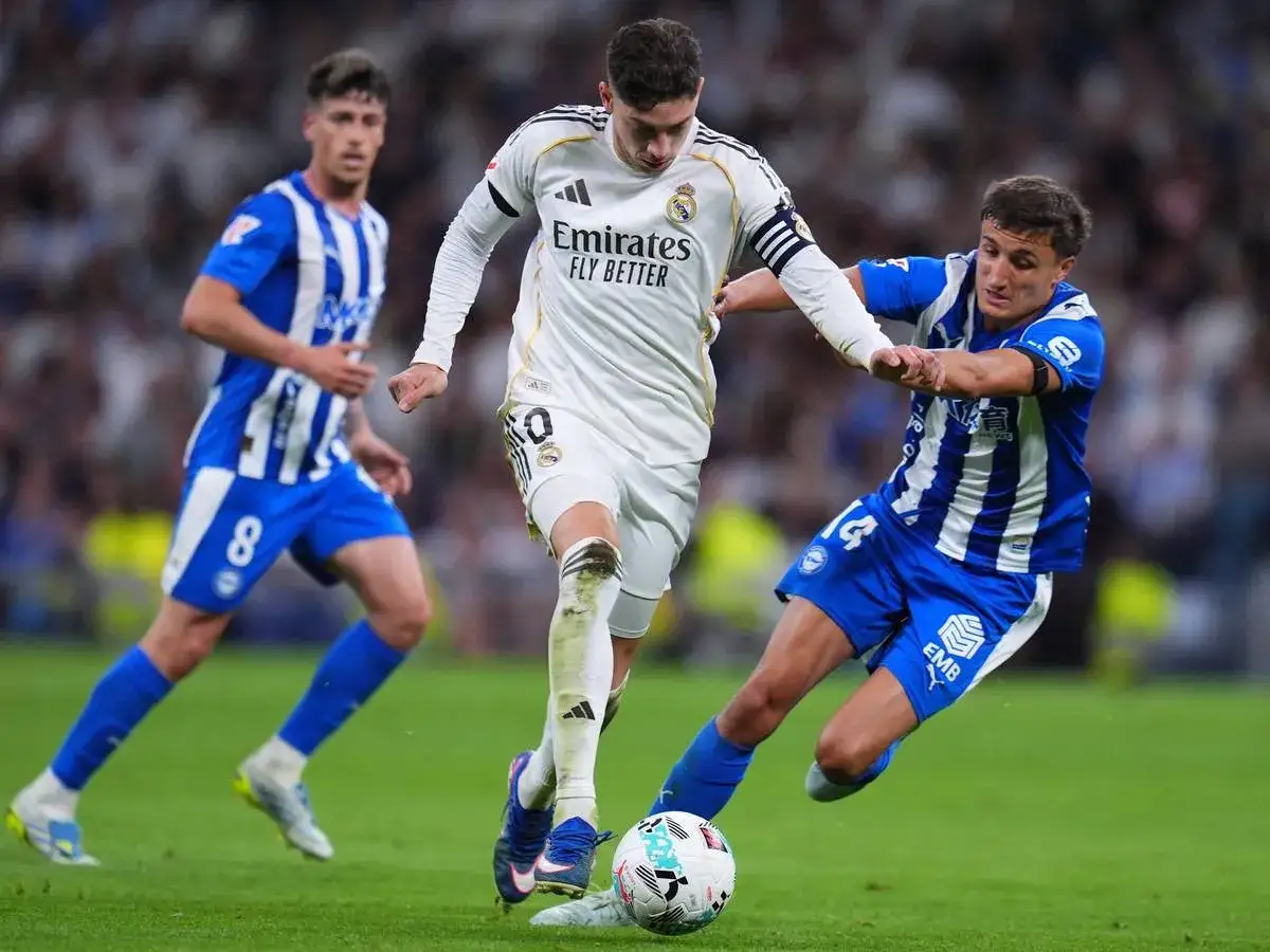 Federico Valverde k&auml;mpft im wei&szlig;en Trikot um den Ball, w&auml;hrend zwei Gegner in blauen Trikots ihn bedr&auml;ngen.