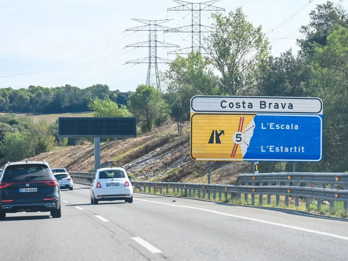 Voyage en Espagne en voiture : panneau Costa Brava, L'Escala, L'Estartit. Des voitures circulent sur l'autoroute.