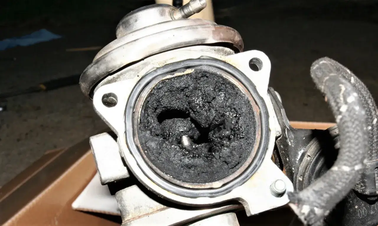Válvula EGR obstruida con carbonilla. El asiento p0401 está completamente cubierto de hollín, impidiendo el paso de gases.