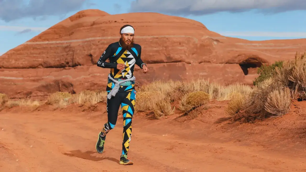 Biegacz w kolorowym stroju pokonuje pustynny teren podczas cross run.