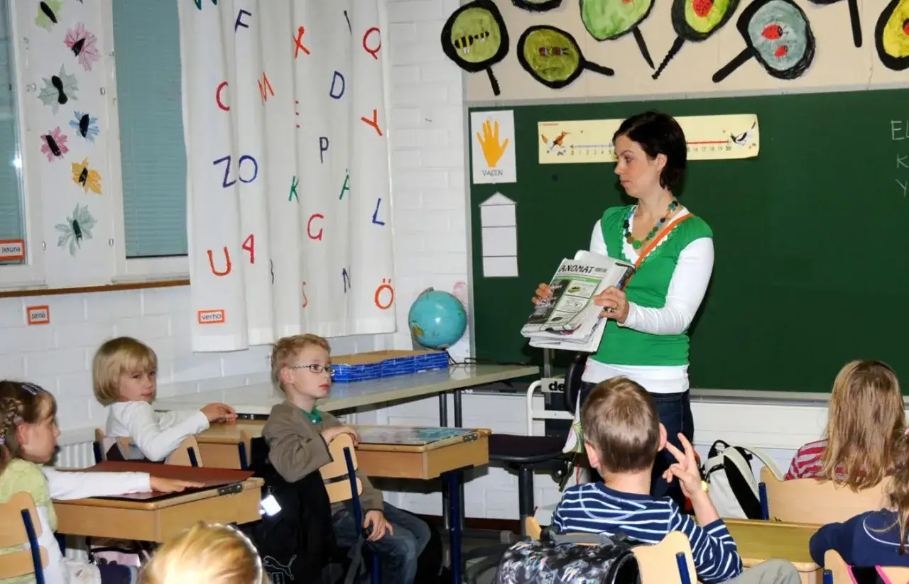 Nauczycielka w Finlandii pokazuje gazetę, a dzieci słuchają. Ciekawe, ile zarabia nauczyciel w Finlandii?