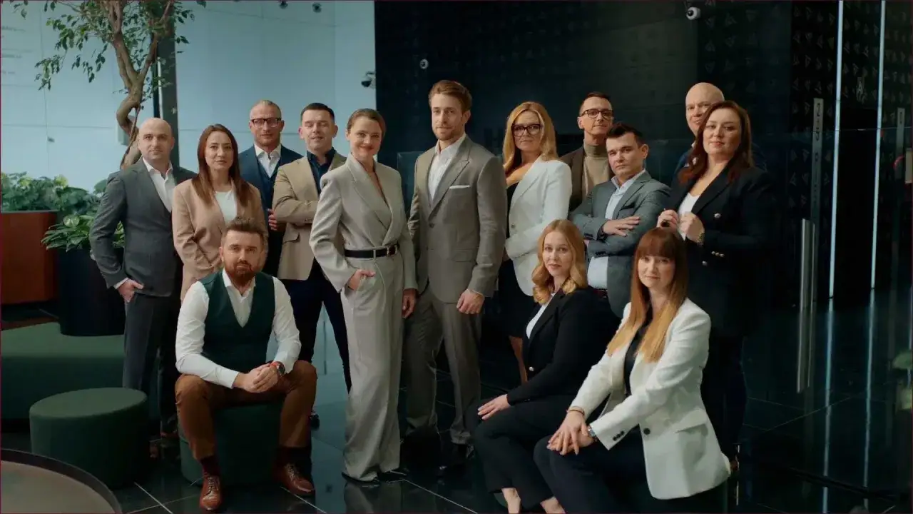 Grupa profesjonalistów w eleganckich strojach pozuje do zdjęcia w nowoczesnym biurze.