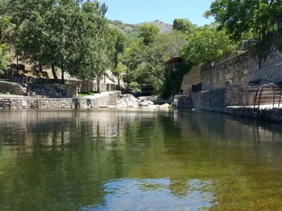 La piscina natural de Casas del Monte, rodeada de vegetaci&oacute;n y construcciones de piedra, invita a un refrescante ba&ntilde;o.