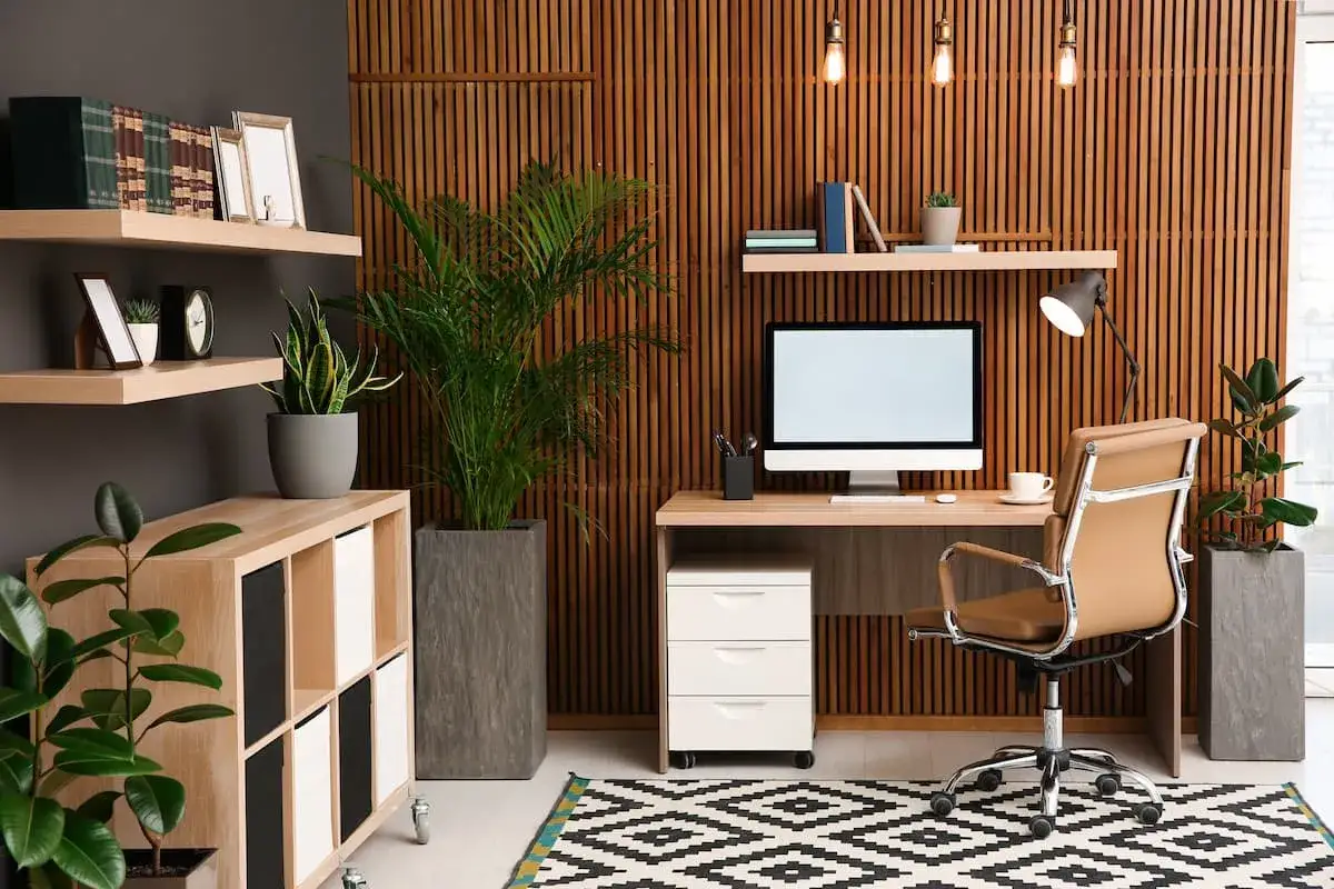 Un moderno angolo smart working con scrivania, sedia in pelle, piante e un tappeto geometrico.