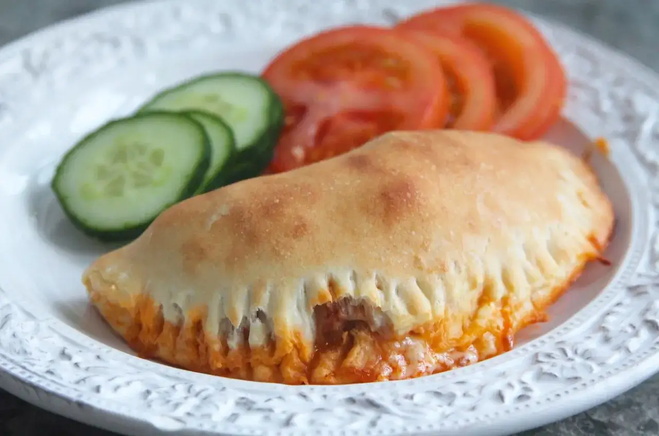 En gyllene pirog med ost och tomatsås, serverad med gurka och tomat. Ett perfekt piroger recept för en snabb och god måltid.