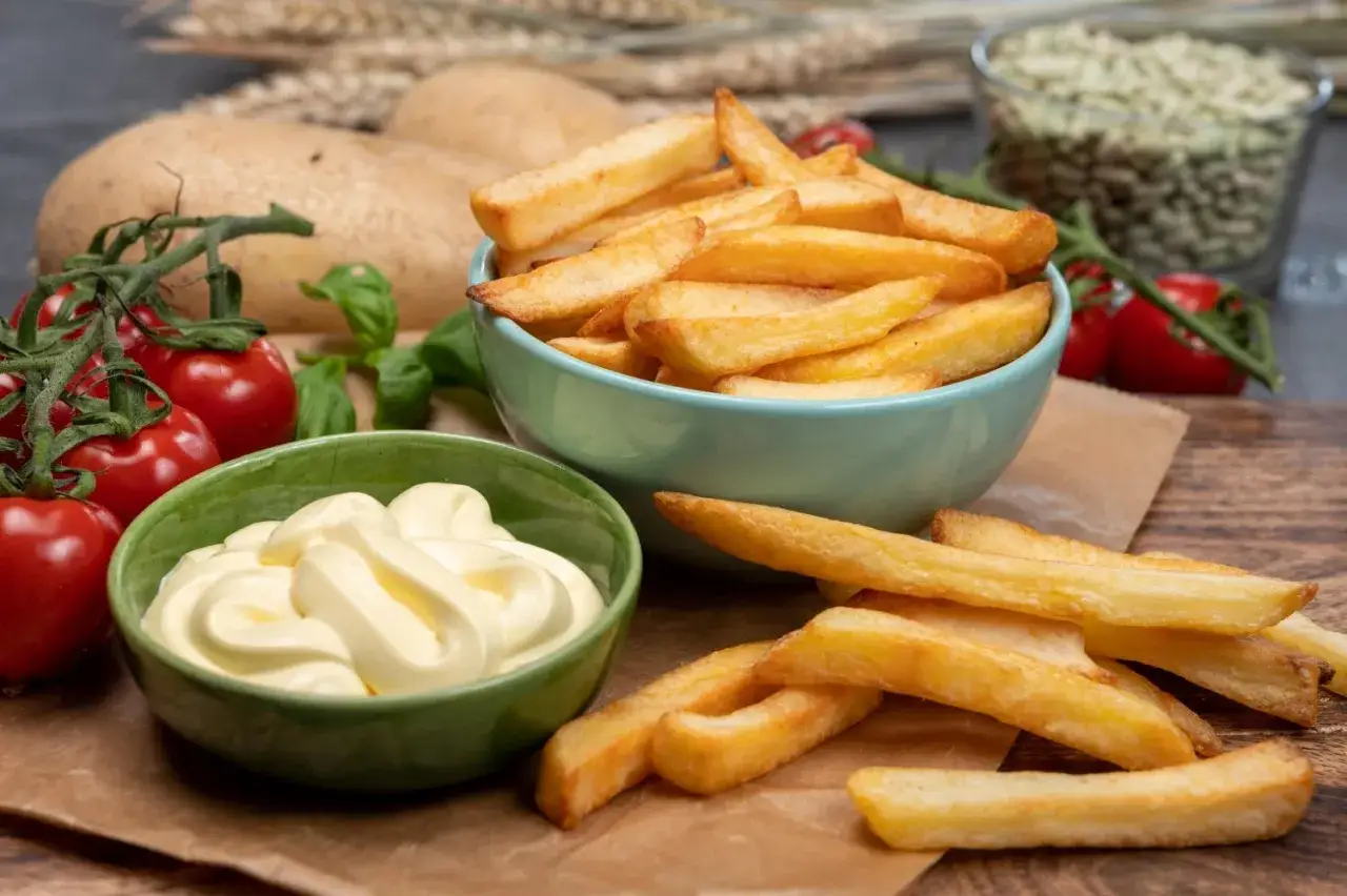 Złociste frytki z McDonald's, podane z majonezem, pomidorkami i ziemniakami w tle. Idealna przekąska!