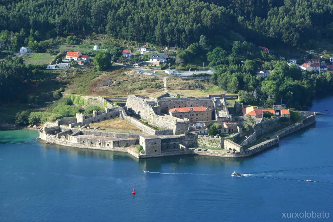 El histórico castillo San Felipe en Ferrol, con sus imponentes murallas de piedra, se alza sobre el agua azul.