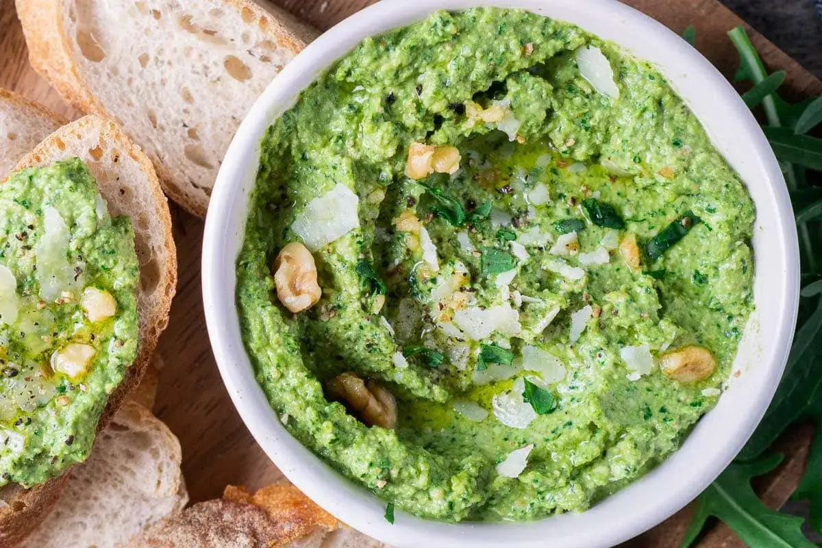 Frisches Rucola Pesto mit Nüssen und Parmesan, serviert mit knusprigem Brot. Ein Genuss für jeden Gaumen!