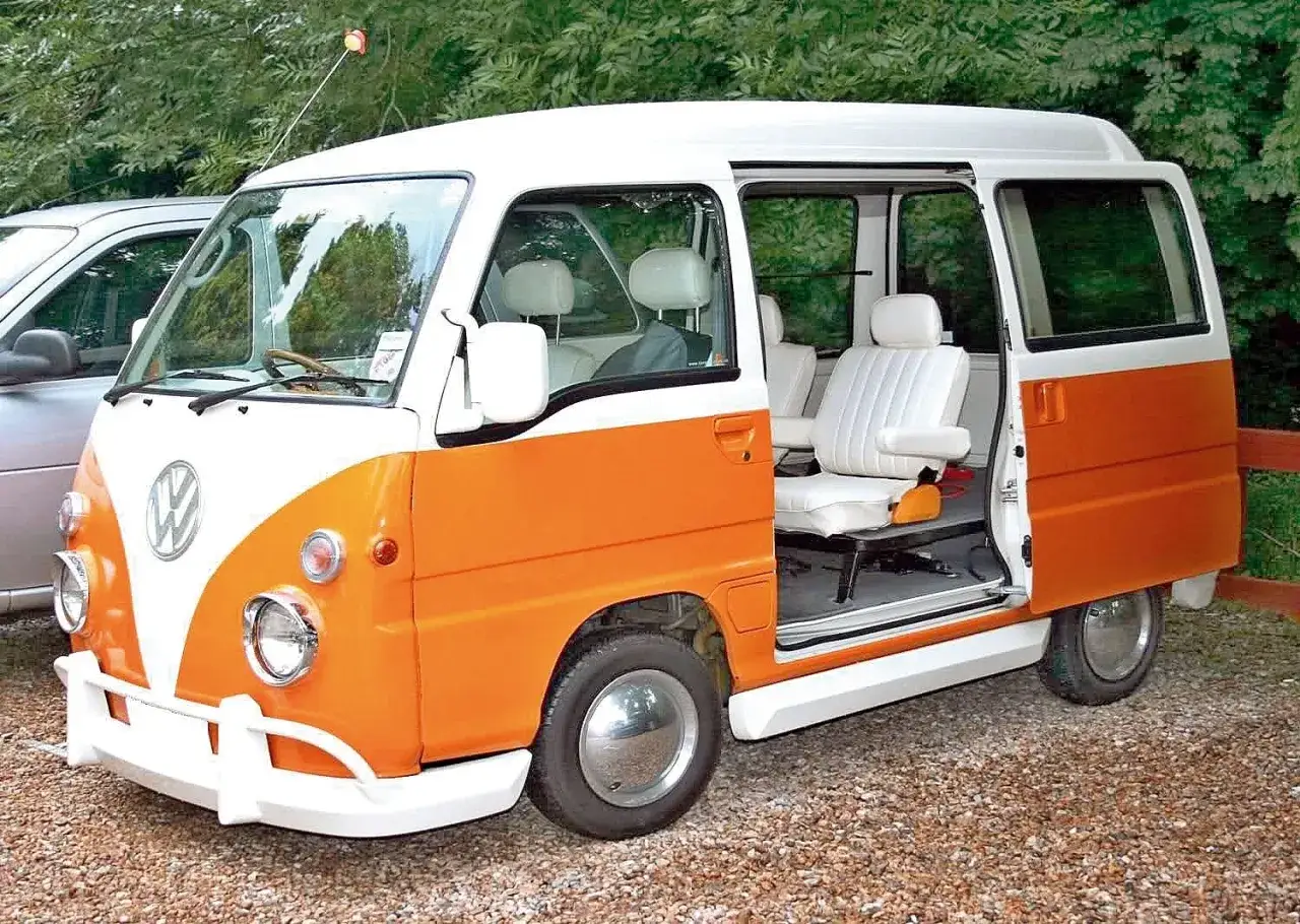 Pomarańczowo-biały kei car z białymi siedzeniami i drzwiami przesuwnymi.