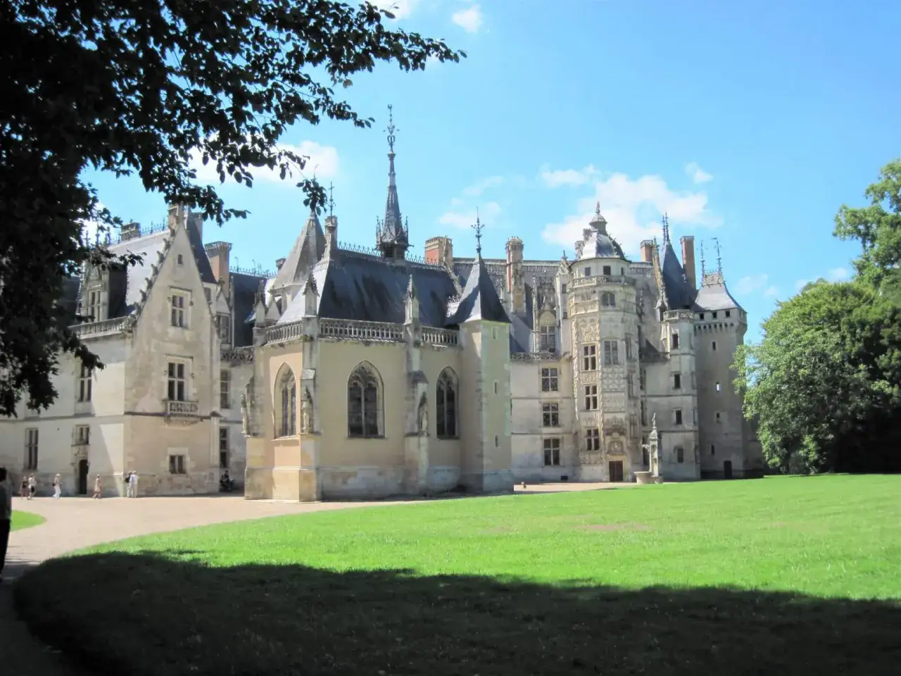 Magnifique château dans le Cher, avec ses tours élancées et son parc verdoyant sous un ciel bleu.