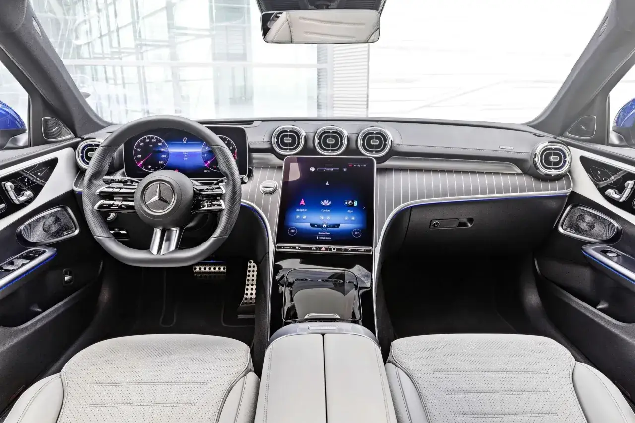 Wnętrze nowoczesnego Mercedesa C180 z dużym ekranem dotykowym i cyfrowymi zegarami.