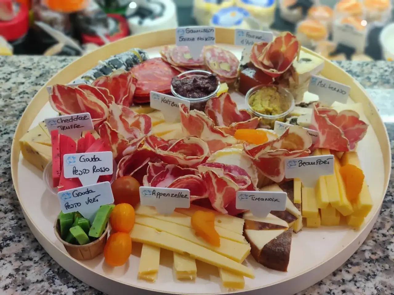 Plateau gourmand : que mettre dans un plateau de charcuterie ? Assortiment de fromages, saucissons, jambons secs, tomates cerises et fruits secs.