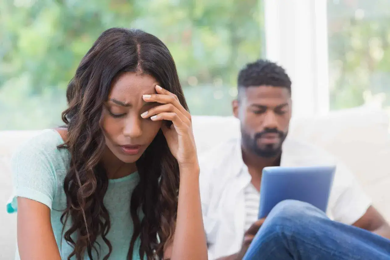 Een vrouw voelt zich niet gesteund door haar partner, die afgeleid is door zijn tablet.