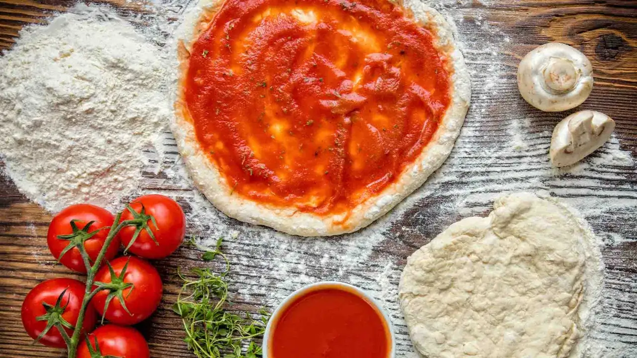 Pizza-Zutaten: Teig, Tomaten, Pilze, Kräuter und Mehl als semola alternative.