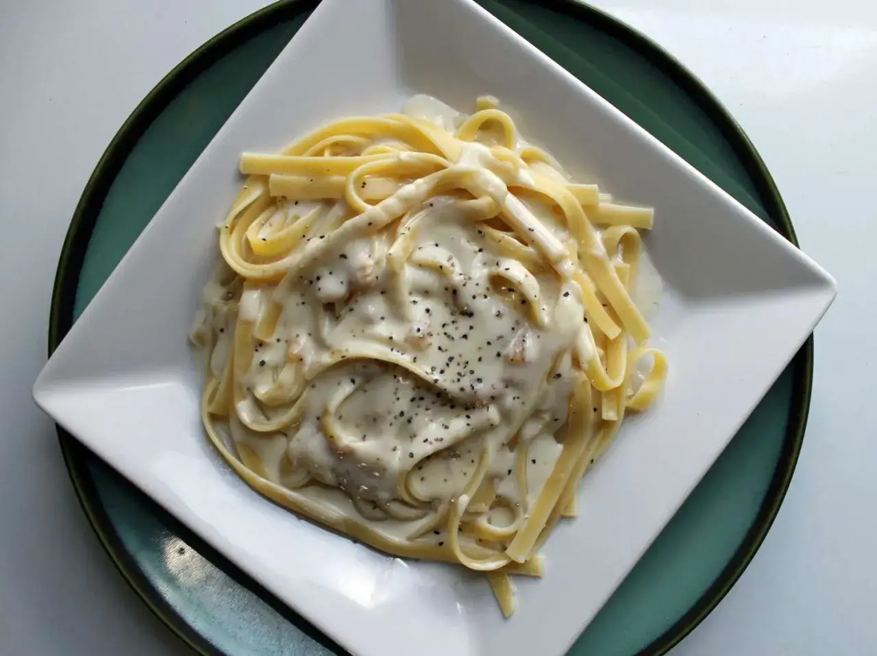 Tagliatelle w kremowym sosie z gorgonzolą i mascarpone, posypane pieprzem. Pyszne danie na talerzu.