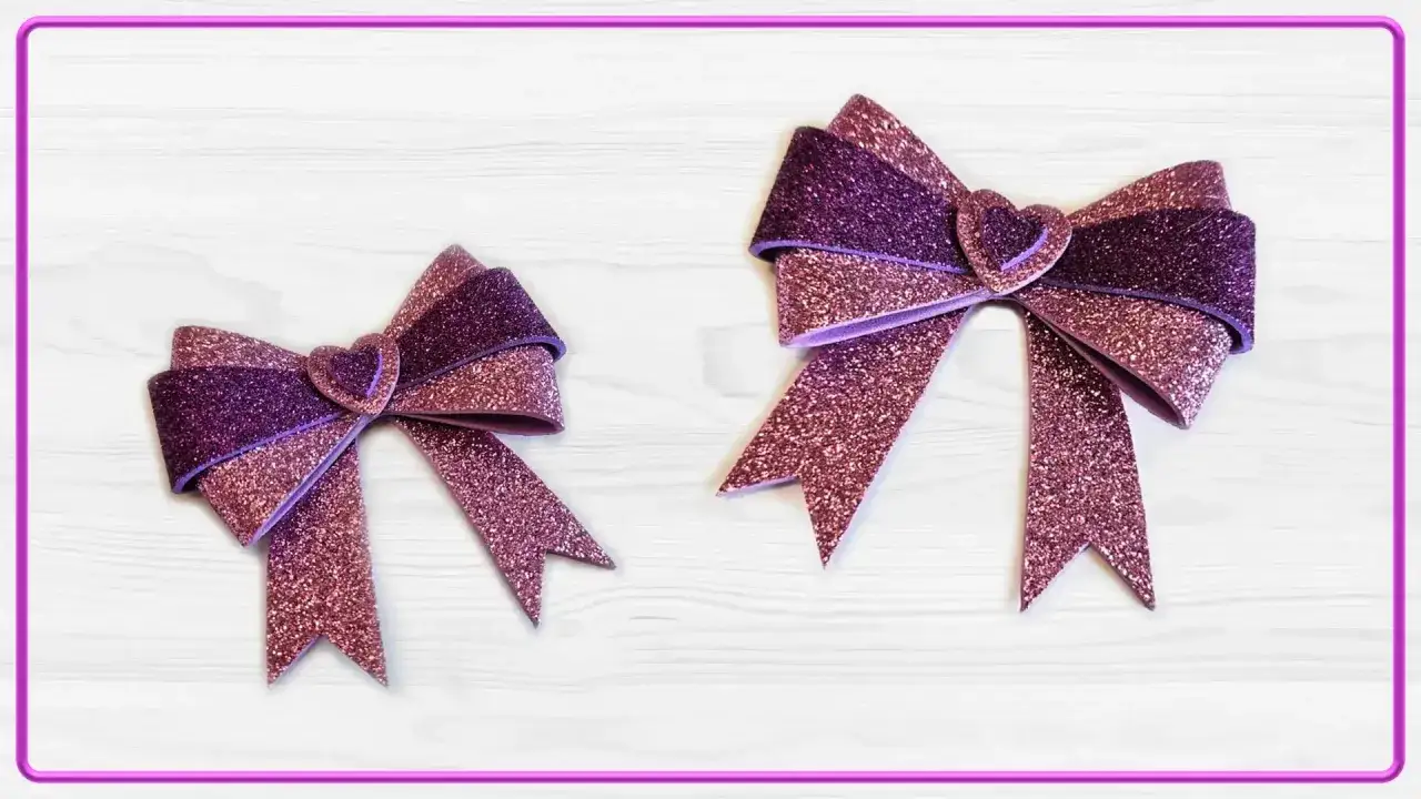 Due fiocchi scintillanti, uno pi&ugrave; grande dell'altro, realizzati con fogli di caucci&ugrave; glitterati viola e rosa, con un cuore al centro.
