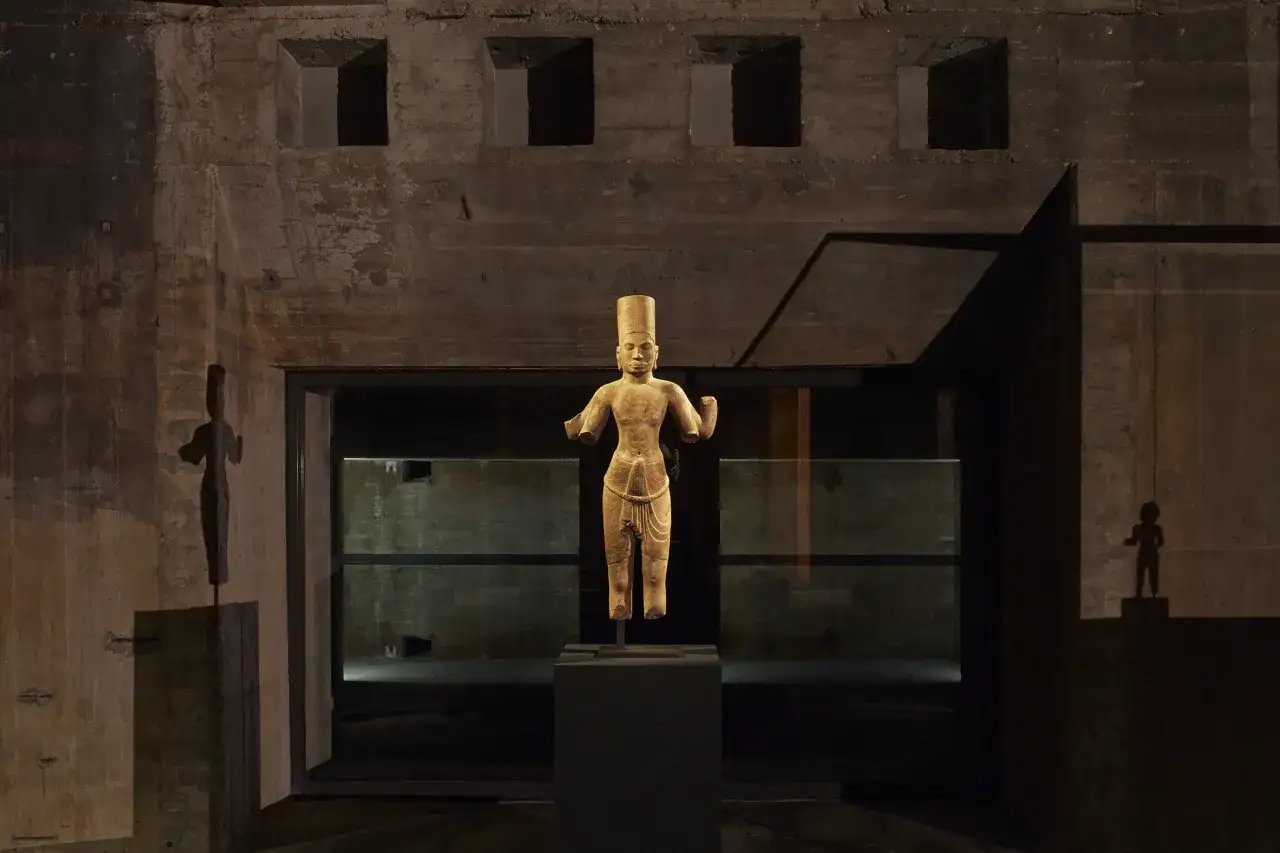 En antik staty st&aring;r i en m&ouml;rk, betongliknande milj&ouml;, kanske en Berlin story bunker. Skuggor av statyn syns p&aring; v&auml;ggarna.