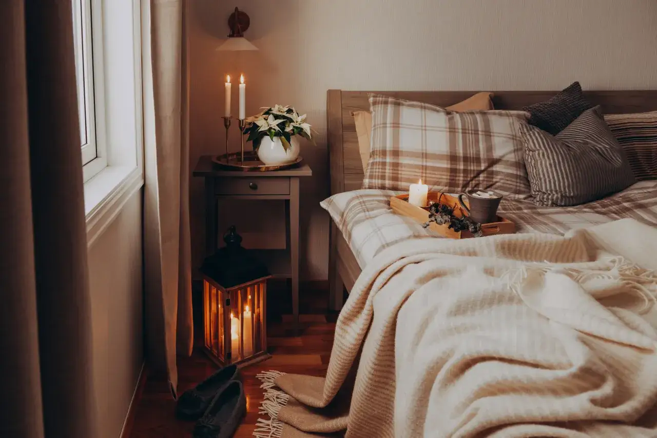 Atmosfera accogliente con candele accese, plaid morbido e dettagli che ispirano idee camera da letto.