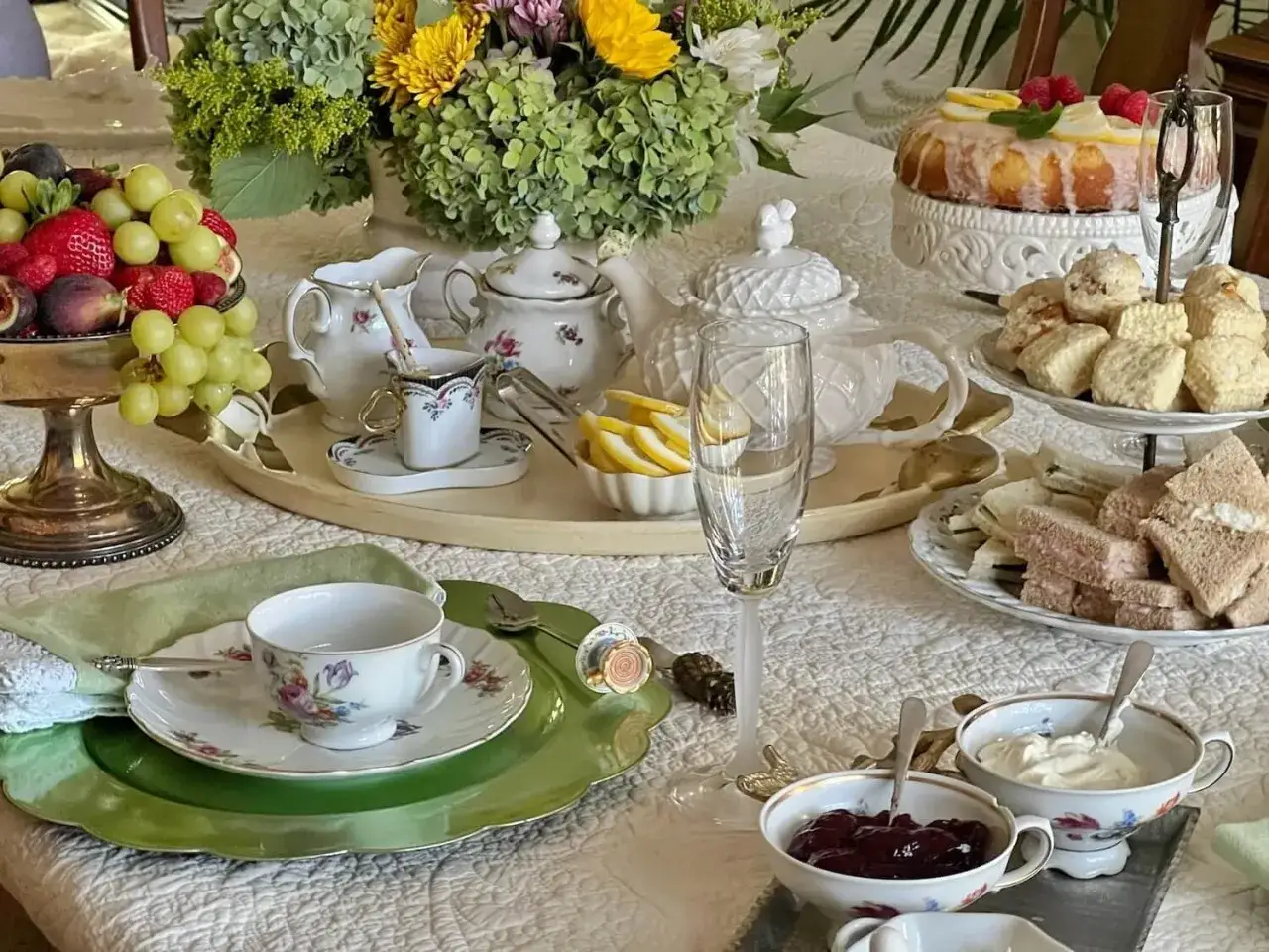 Elegancki st&oacute;ł do herbaty z ciastem cytrynowym, scones, kanapkami i owocami. Czy herbata wysusza gardło? Tutaj wszystko wygląda na nawilżające.