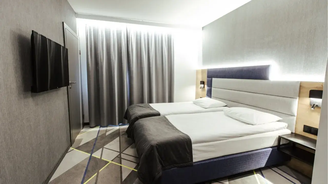 Nowoczesny pokój hotelowy w Warszawie z dwoma łóżkami, telewizorem i stylowym dywanem. Idealny na pobyt w courtyard hotels Warsaw.