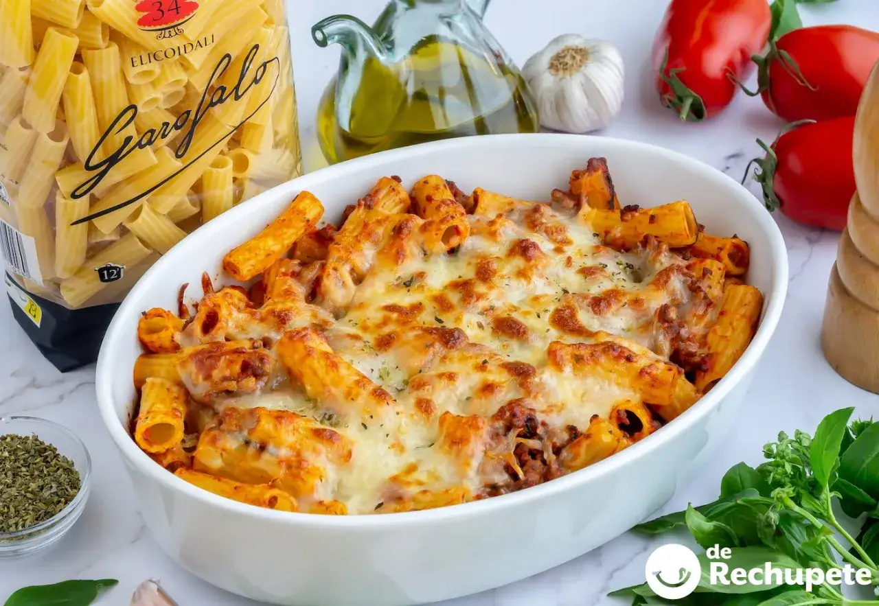 Espaguetis con carne picada gratinados, listos para disfrutar. Acompañados de ingredientes frescos como tomates y albahaca.