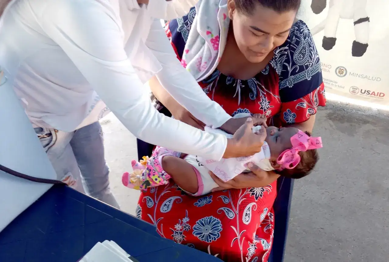 En mamma håller sitt barn för vaccin i Colombia.