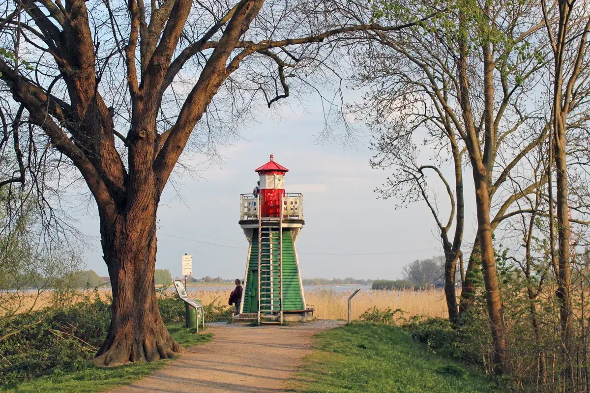 Ein kleiner Leuchtturm mit rotem Dach und grüner Basis steht am Wegesrand. Ein schöner Ort für einen Ausflug im Winter, um die Natur zu genießen.