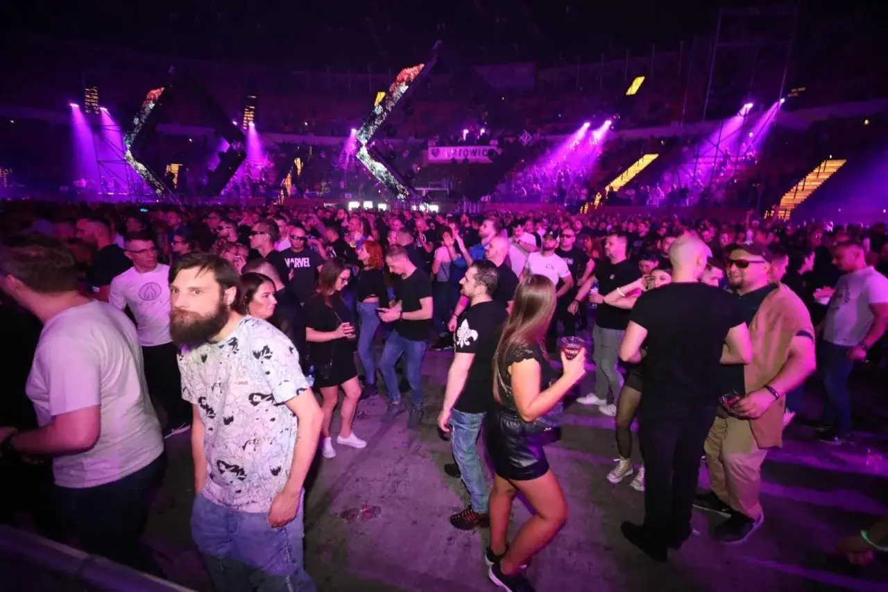 Tłum ludzi na koncercie Mayday Poland w Katowicach, rozświetlony fioletowymi światłami sceny.
