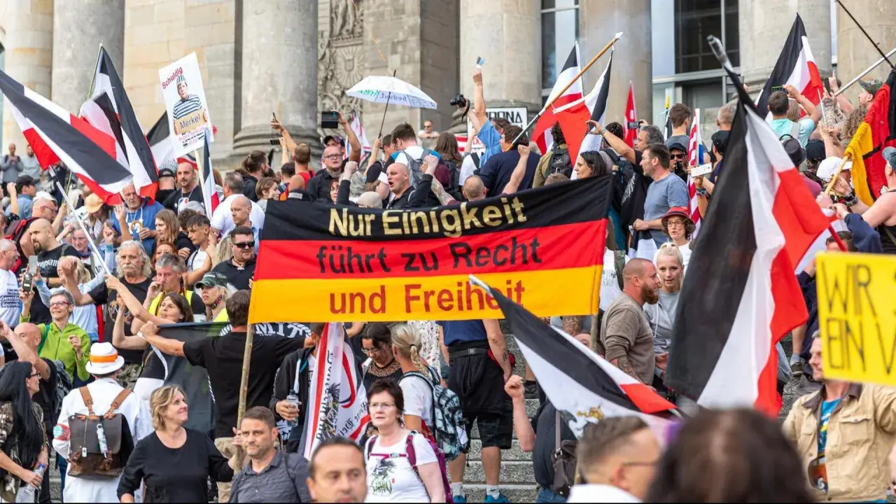 Menschenmenge mit deutschen Fahnen und einem Banner