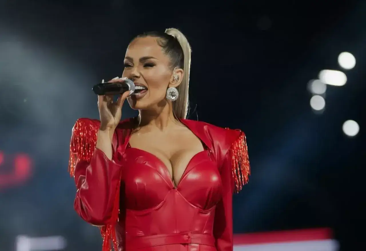 Paula Karpowicz w czerwonym, błyszczącym stroju z frędzlami na ramionach śpiewa do mikrofonu. Jej wiek nie przeszkadza jej w energetycznym występie.