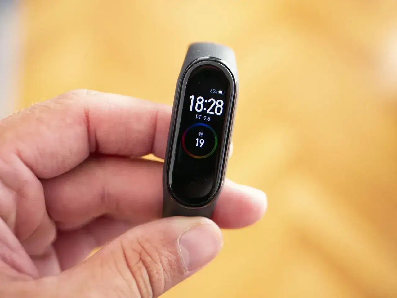 Dłoń trzyma opaskę Mi Band 4 z wyświetloną godziną 18:28 i tętnem 79. To najlepsza aplikacja do mi band 4.