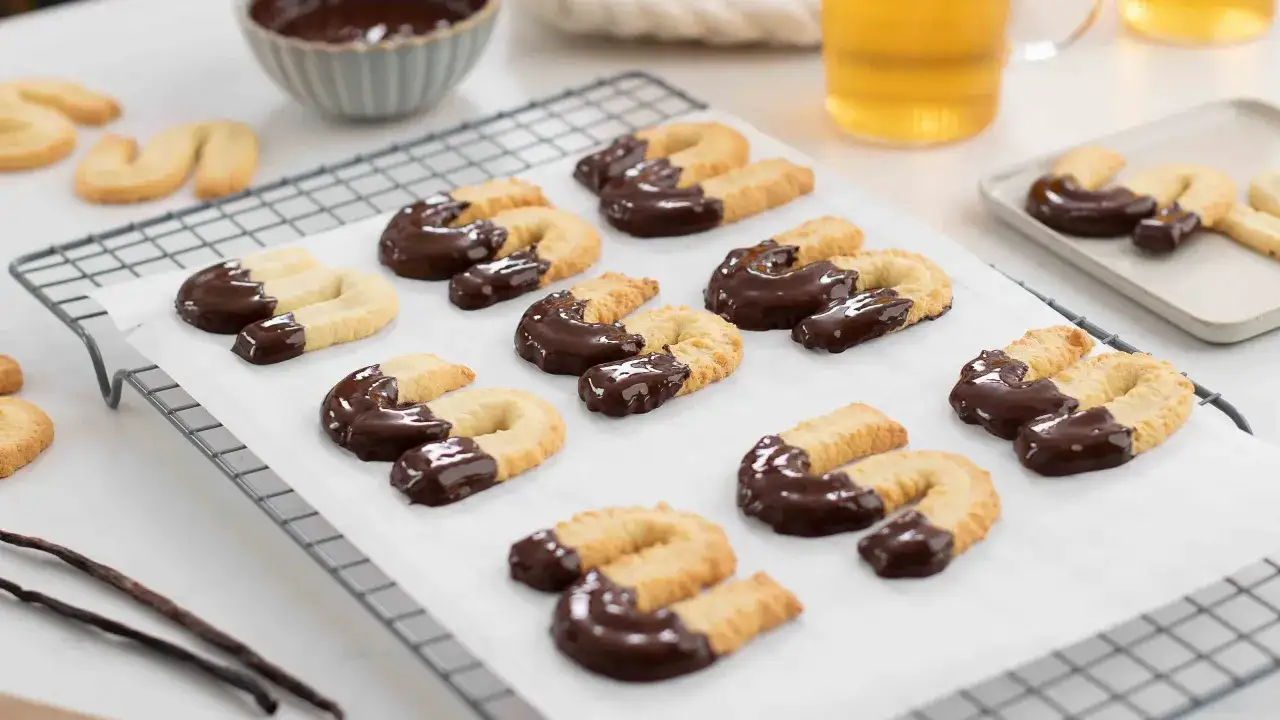S-formade sm&aring;kakor, h&auml;lften doppade i m&ouml;rk choklad, redo att avnjutas. Ett perfekt cookies recept f&ouml;r fikat.