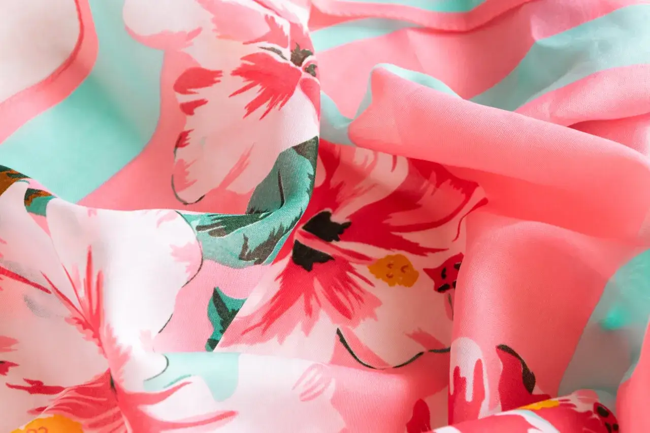 Ein zartes, fließendes Textil mit einem lebendigen Blumenmuster in Pink und Türkis. Der **digitaldruck textil** zeigt detailreiche Blüten, die auf dem Stoff wie gemalt wirken.