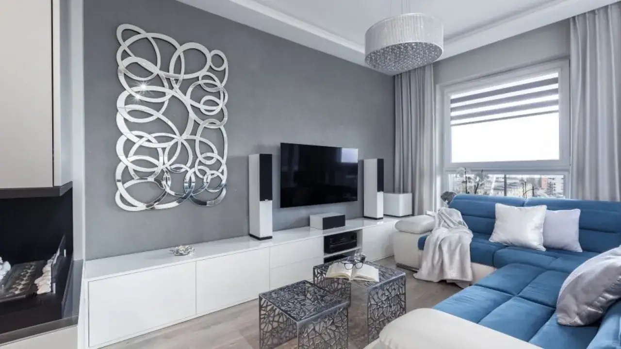 Nowoczesny salon z niebieską kanapą i szarymi ścianami. Widać, jakie kolory pasują do szarego, tworząc elegancką przestrzeń.