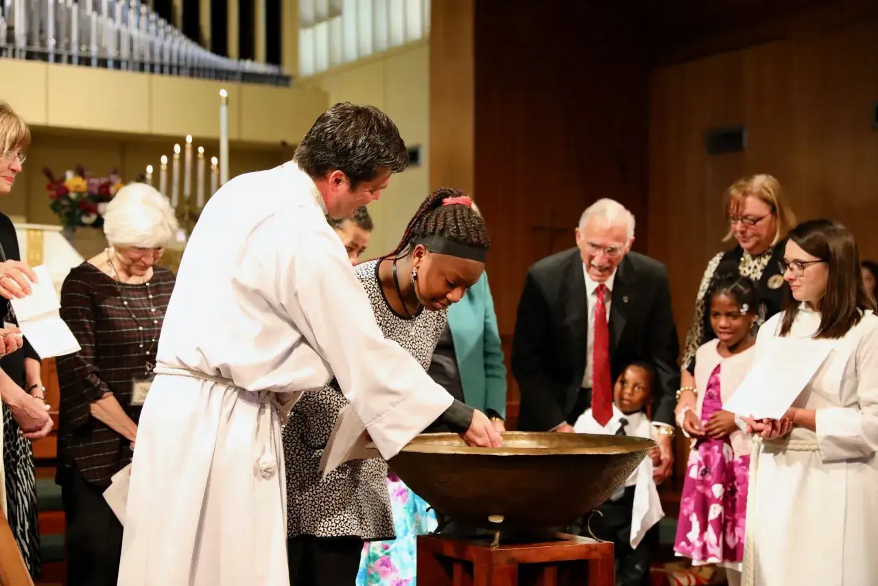 A baptism ceremony, a key aspect of the 5 fold ministry, unfolds as a minister blesses a young girl in a church.