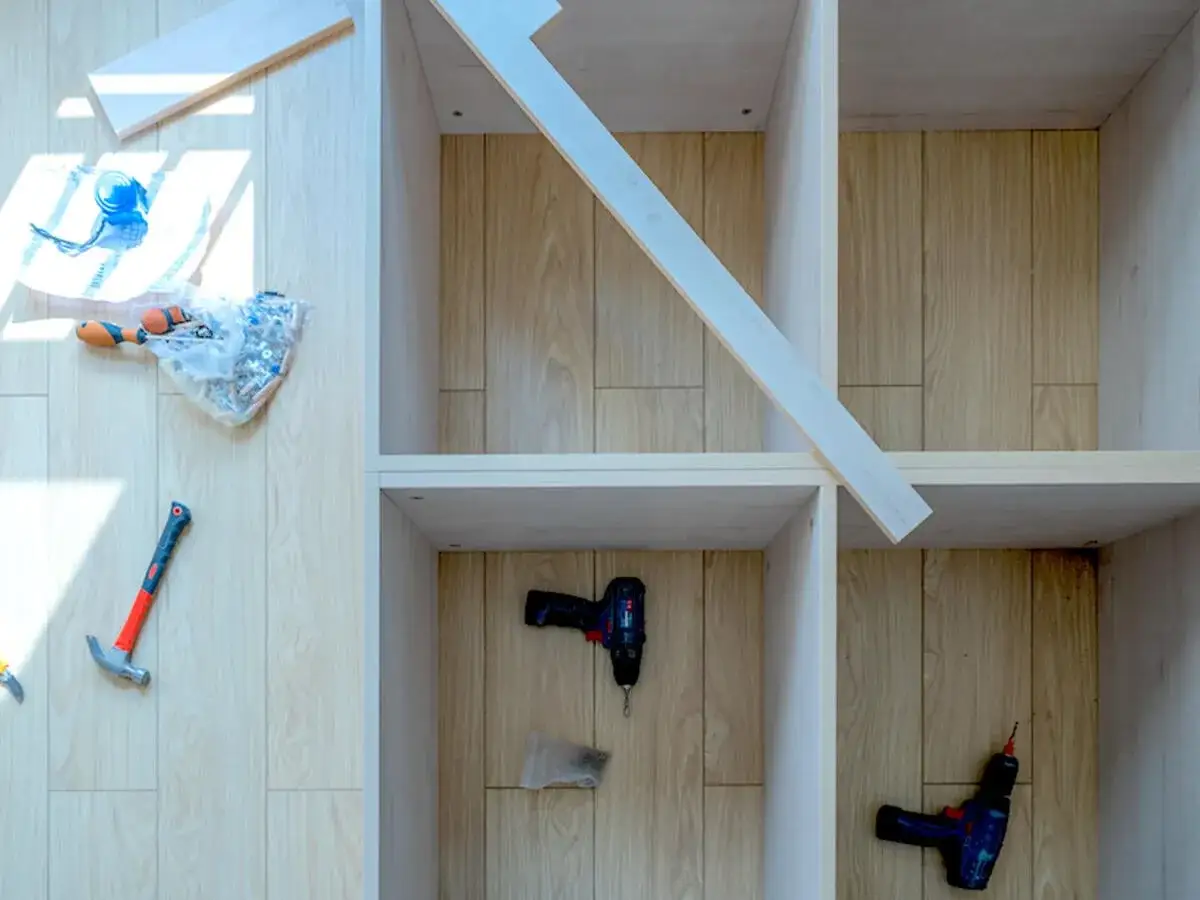 Werkzeug und Schrauben liegen bereit, um einen Einbauschrank selber bauen. Ein Hammer und zwei Akkuschrauber sind zu sehen.