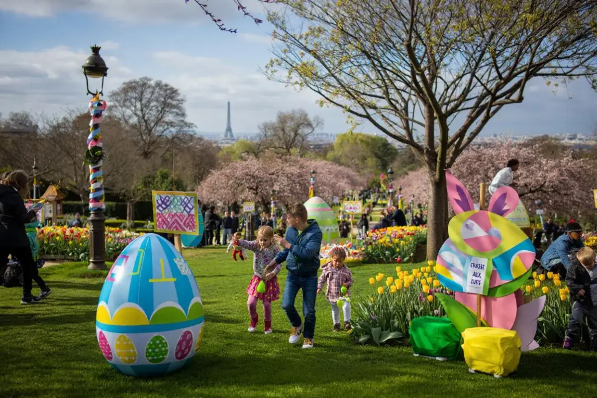 Joyeuse chasse aux œufs à Paris, avec des enfants joyeux dans un parc fleuri, sous le regard de la Tour Eiffel.