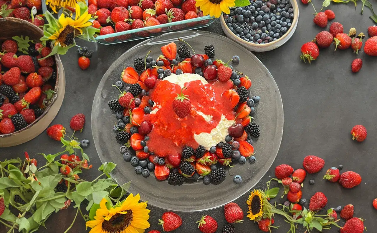 Ein k&ouml;stliches Joghurtbombe Rezept mit frischen Erdbeeren, Blaubeeren und Kirschen, umgeben von Sonnenblumen.