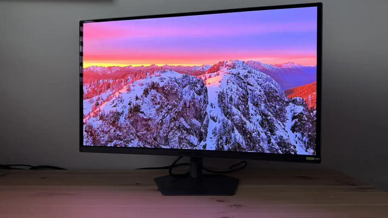 Monitor Gigabyte z pięknym zimowym krajobrazem górskim w rozdzielczości 2k. Zachód słońca maluje niebo na różowo i fioletowo.
