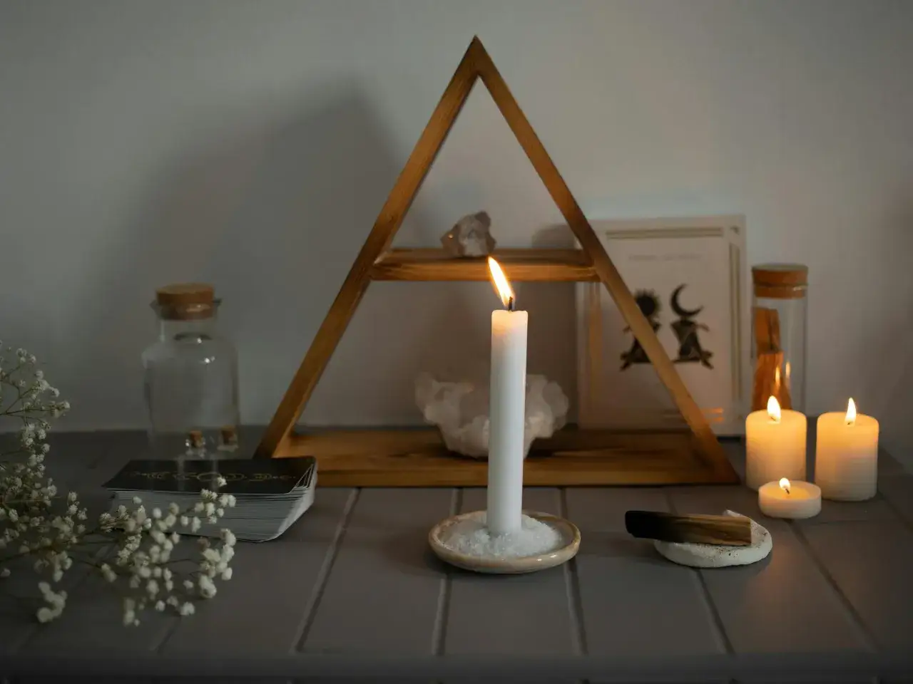 Un altar m&iacute;stico con una vela de palo santo para que sirve en la purificaci&oacute;n, cartas de tarot, cristales y velas encendidas.
