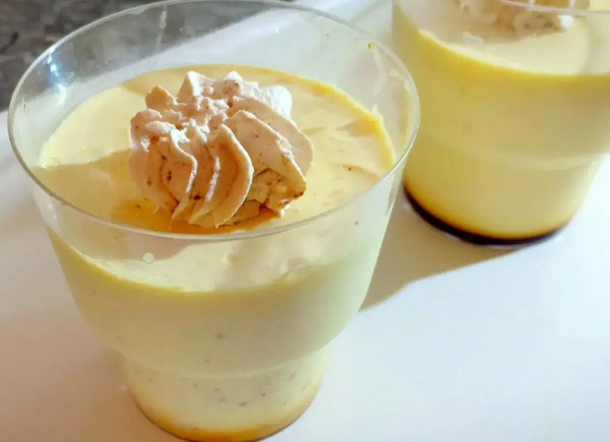 Dwa deserki creme caramel w szklanych pucharkach, jeden z bitą śmietaną.
