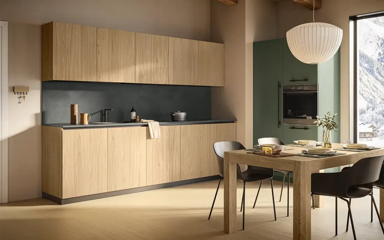 Cucina moderna con ante in legno chiaro, piano scuro e tavolo in legno. Un'idea per rinnovare cucina in legno con stile.