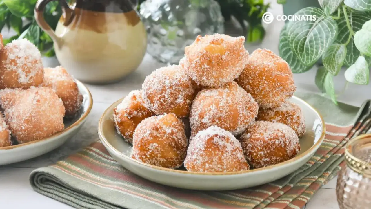 Montón de buñuelos de manzana espolvoreados con azúcar, listos para disfrutar.