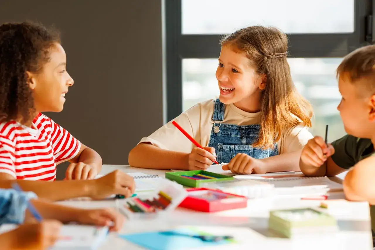 Bambini sorridono e disegnano, mostrando una mentalit&agrave; di crescita e collaborazione.