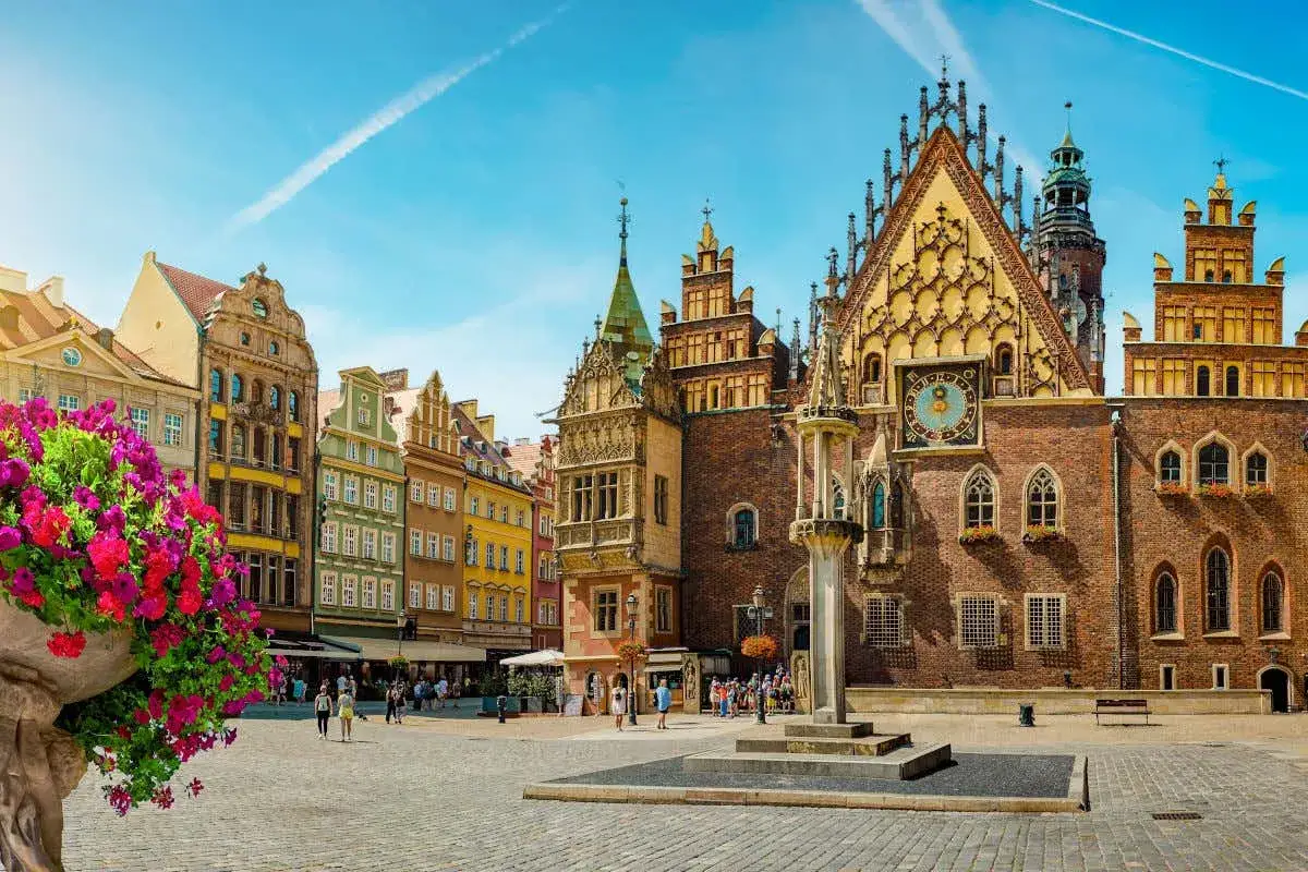 Plaza del Mercado en Breslavia, Polonia, con edificios históricos y flores vibrantes.