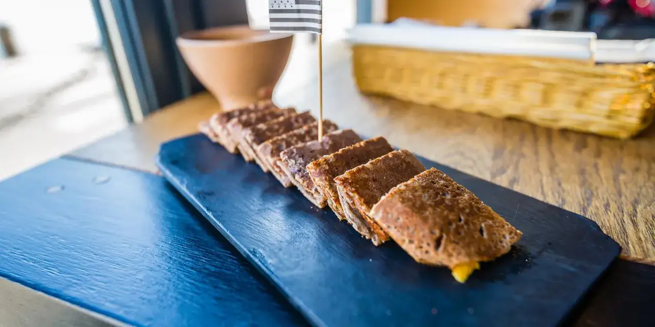 Galettes bretonnes coupées en tronçons, garniture visible, sur ardoise. La farine de blé noir, naturellement sans gluten, est à l'honneur.