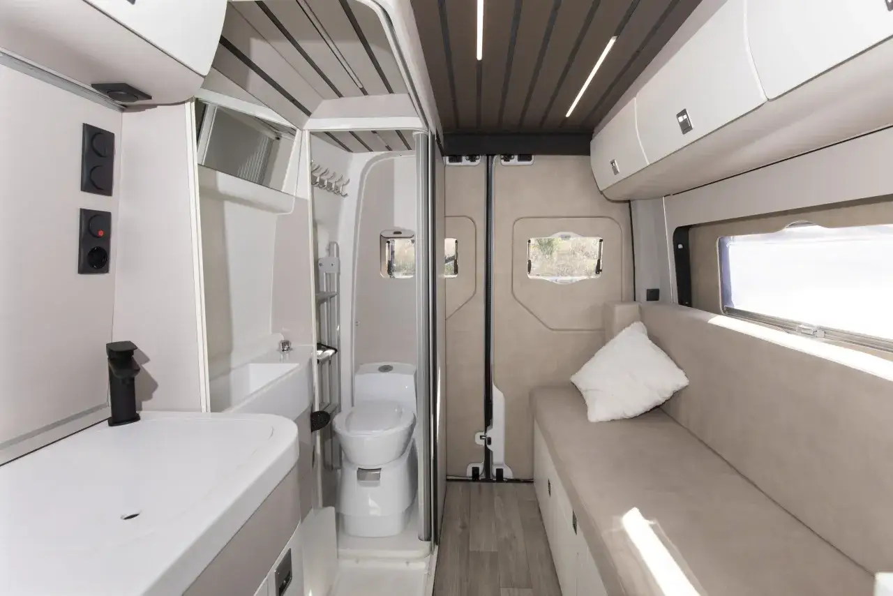 Interior de camper con baño completo, lavabo y asiento. Ideal para quienes buscan los mejores camper con baño para sus viajes.